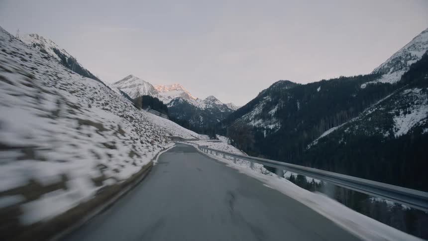 Vehicle drives along winding road in the snowy mountains