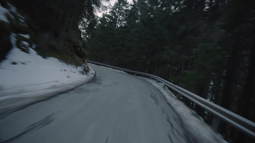 Road clings to side of mountain with forest and drop on one side an incline on the other