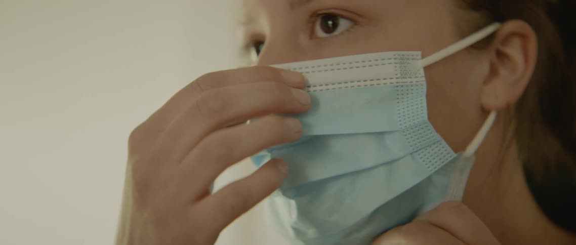 A young girl puts a mask on