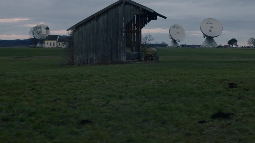 Telescopes in a large field with a church and shed