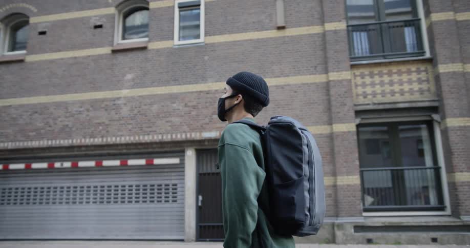 Asian man wearing a black face mask walks down the street in the city