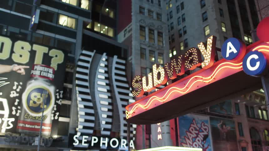 The subway sign is lit and flashing in the city