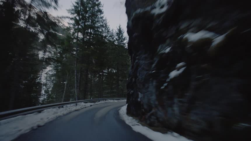 Vehicle drives along the winding narrow road in the snowy mountains