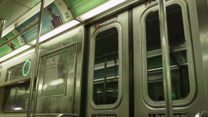Lights flash outside the doors of a moving subway train in a tunnel