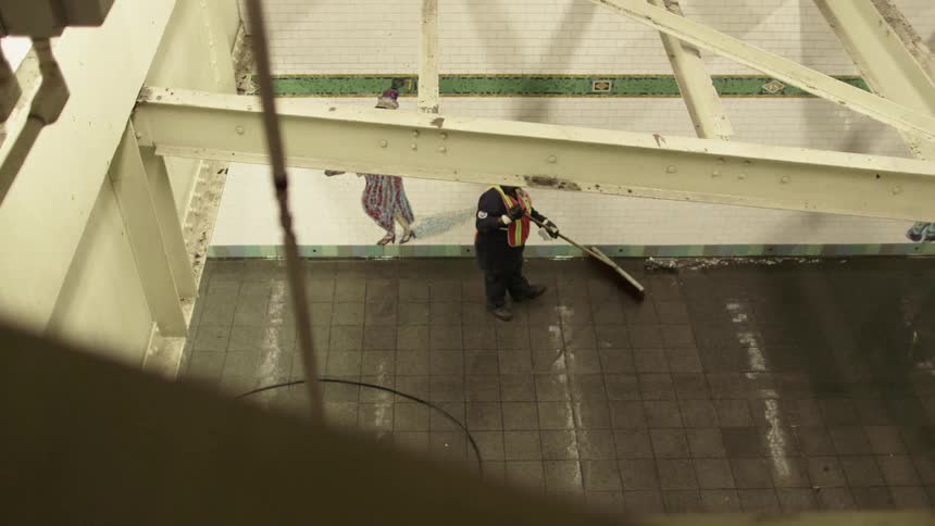 Man cleans ground near elaborately dressed female figure