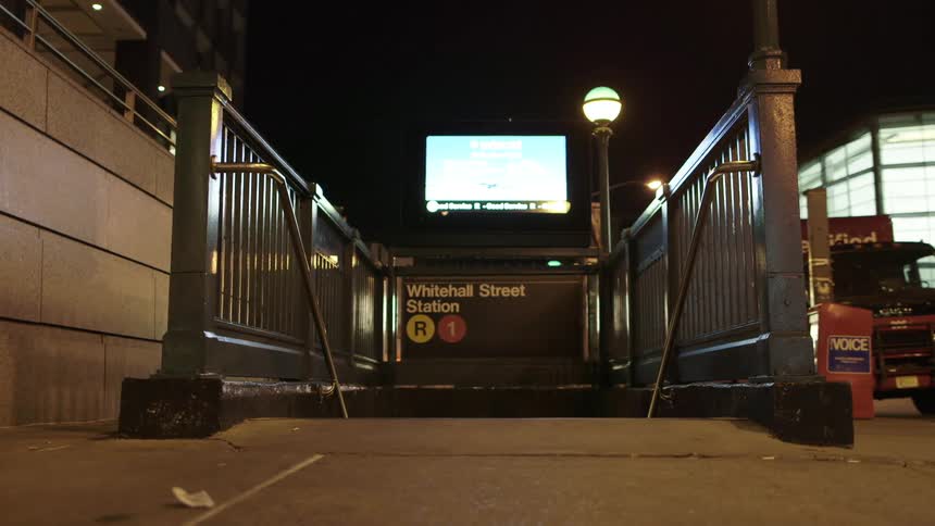 A digital billboard flashes above a staircase to the subway
