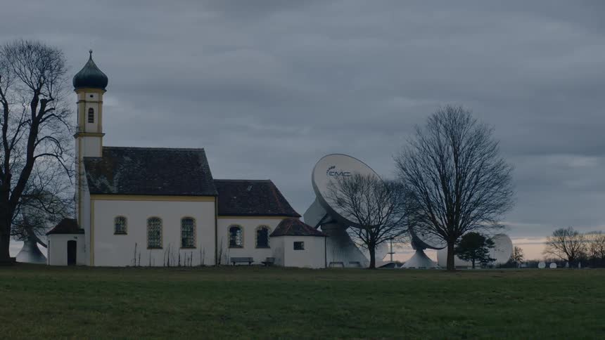 The building is surrounded by satellite dishes on the field