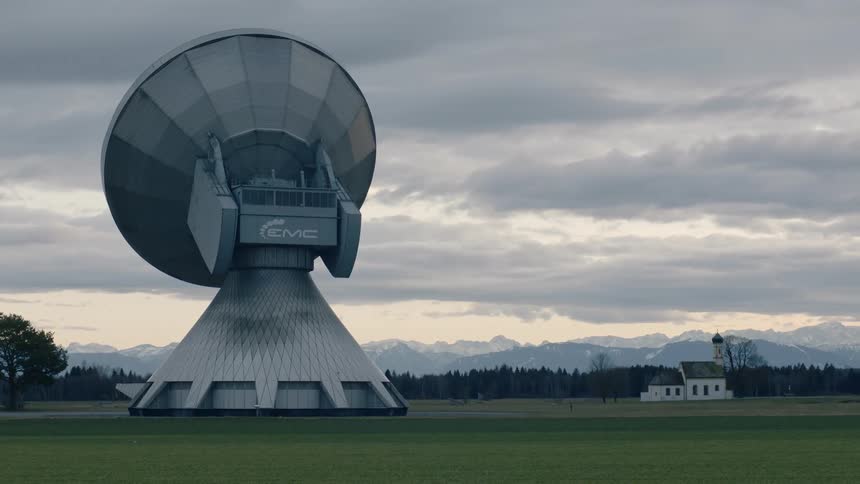 A large satellite dish sits on the field