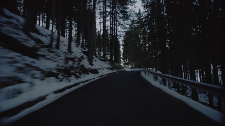 Vehicle drives along the road in the snowy hills