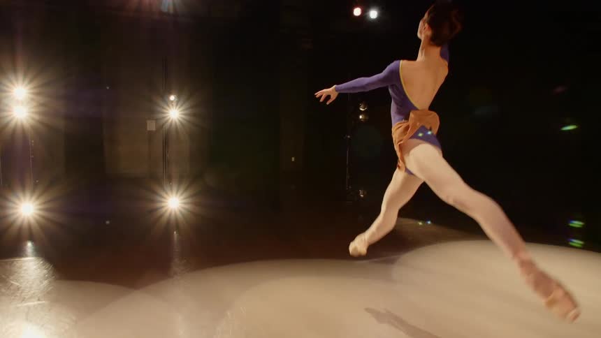 A woman dancing and leaping on stage