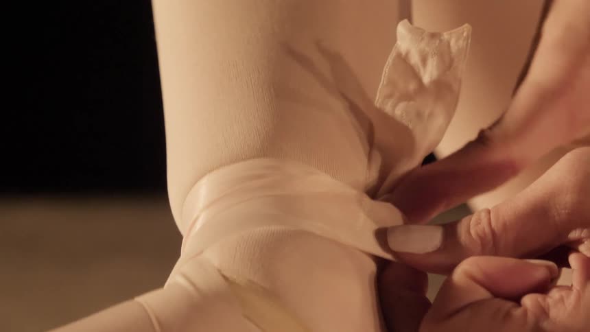Dancer tying the straps of ballet slippers into a knot