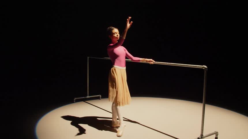 Dancer practicing at balance bar under a spotlight on stage