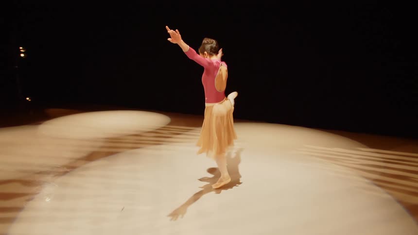 Ballerina performs on stage in circle of light