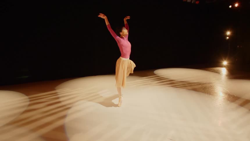 Ballerina twirls and dances in a spotlight