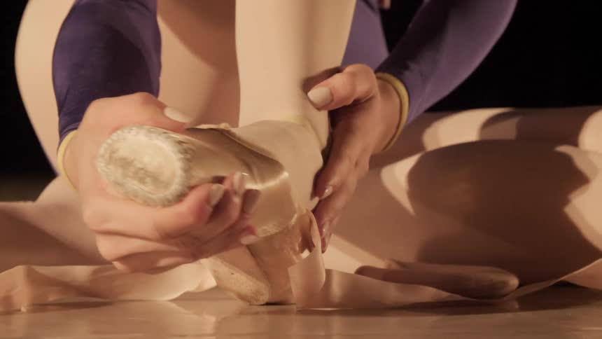 A ballerina ties her shoes