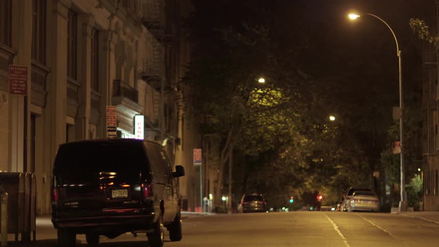 Vehicles remain parked on empty street at night