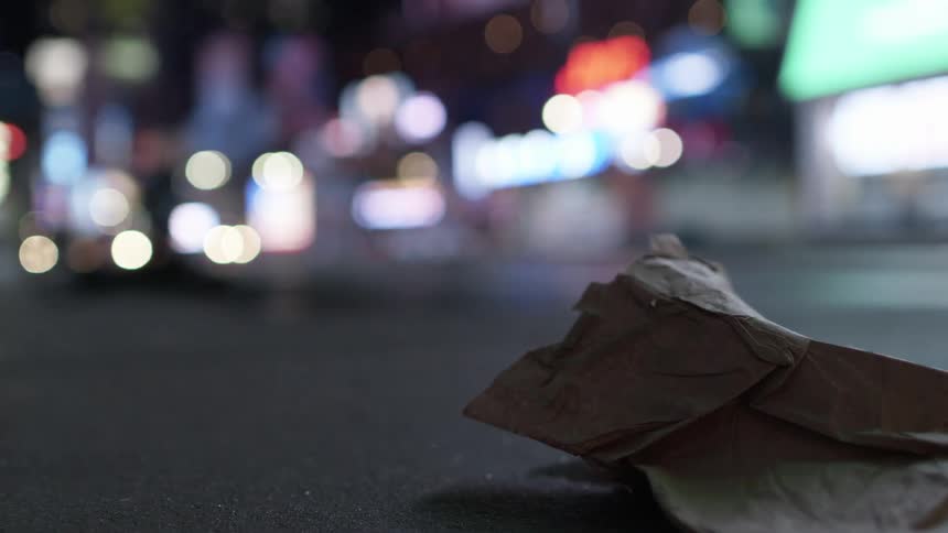 A crushed brown paper bag on the ground in a city during the night
