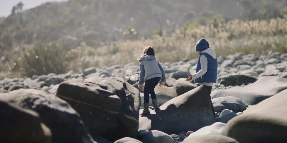 A girl jumps from one rock to another