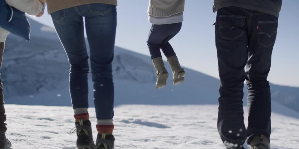Family hikes on the snowy mountain on a sunny day
