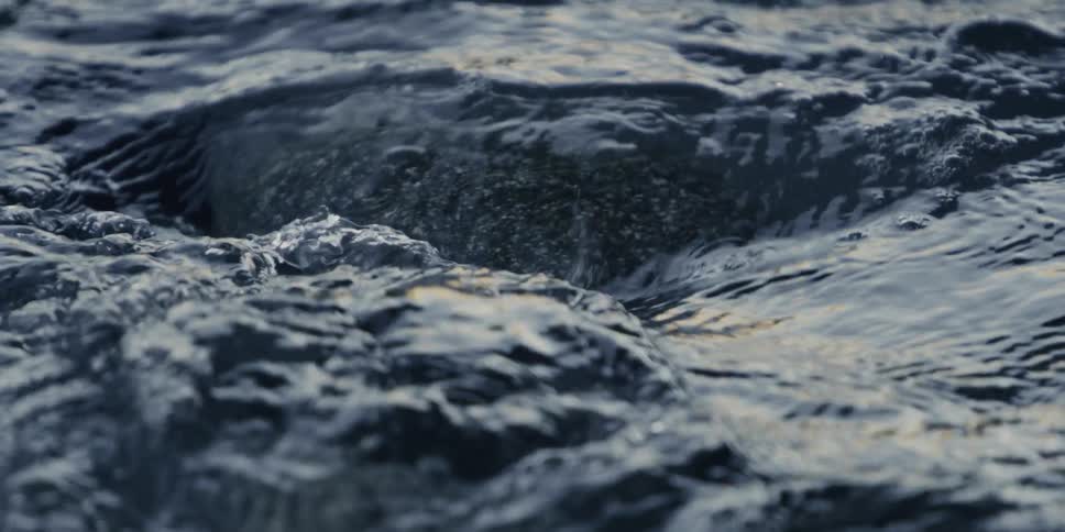 A rock being covered by a wave of water