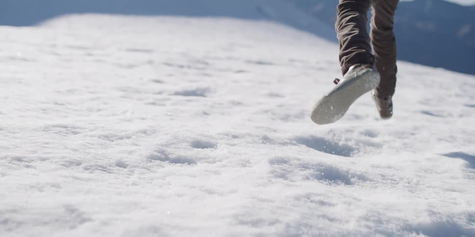Man runs over the snowy ground on top of a mountain