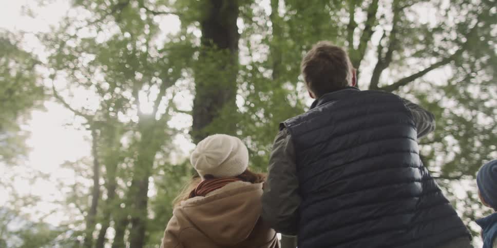 A family gathers outside looking up to the sky and trees