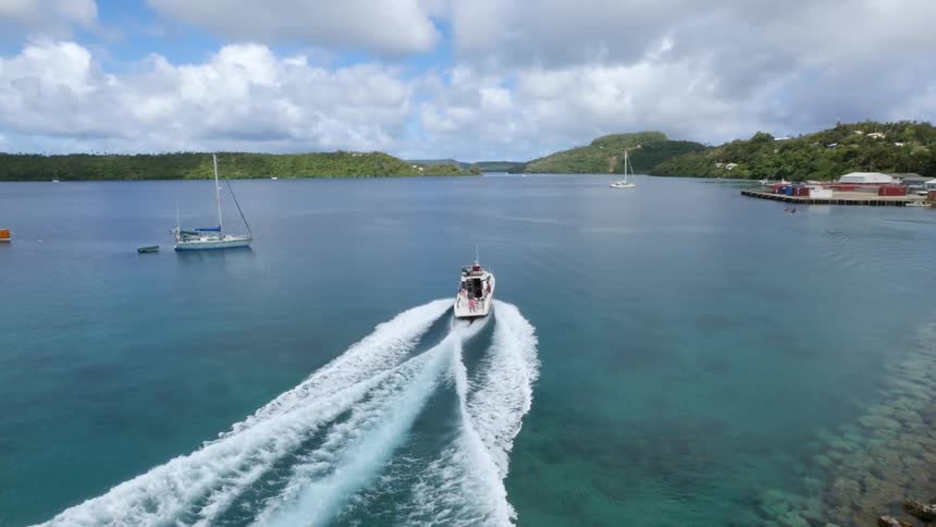 A boat travels across water on a mostly cloudy day