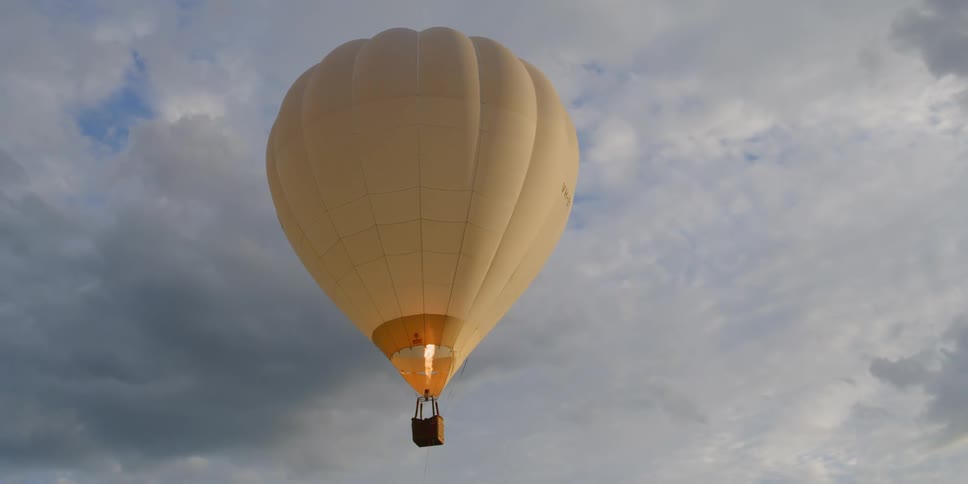 Hot air balloon drifts across a cloudy sky