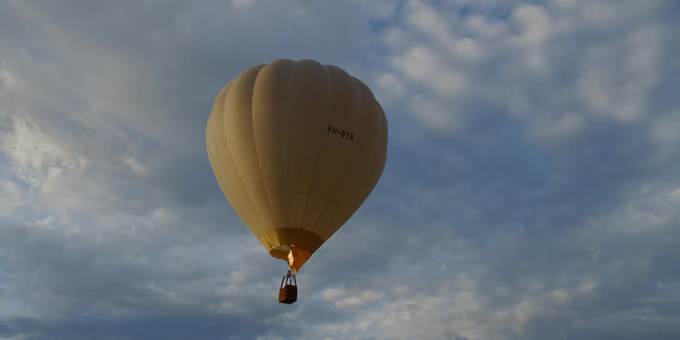A yellow hot air balloon floating in the sky