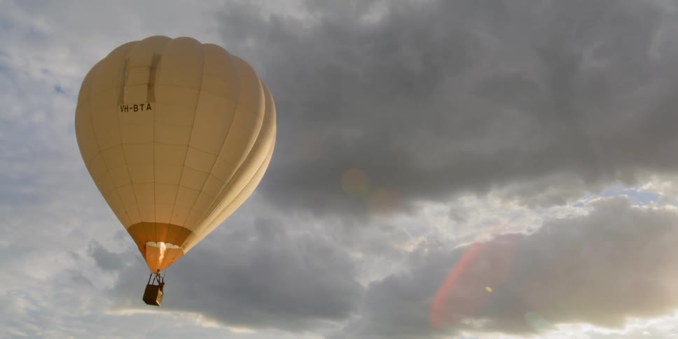 The hot air balloon travels in the cloudy sky