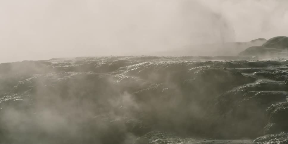 Steam rising from rough ground filling the air as liquid flows through crevices