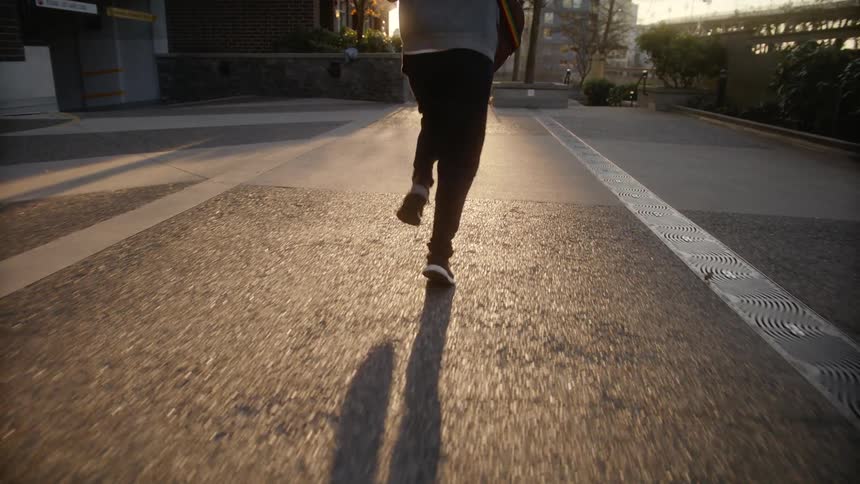 Man runs through park on city at sunset