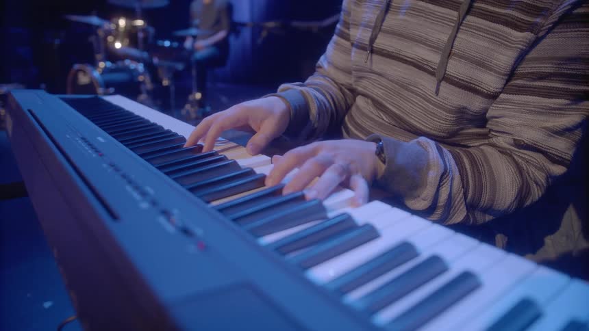 Musicians playing instruments on stage under colored lighting