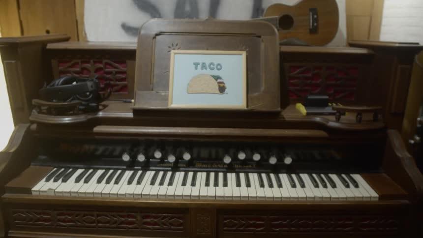 Vintage piano on display in an antique store with a vintage taco sign