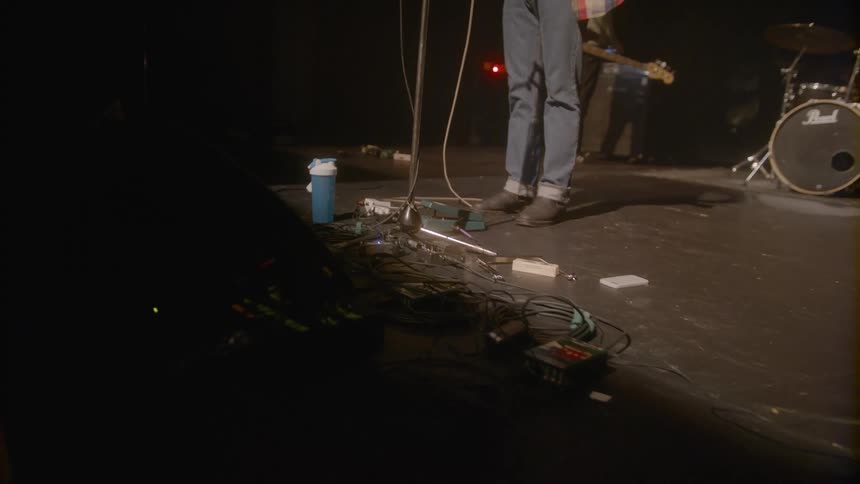 A man stands on a stage in front of a set of drums