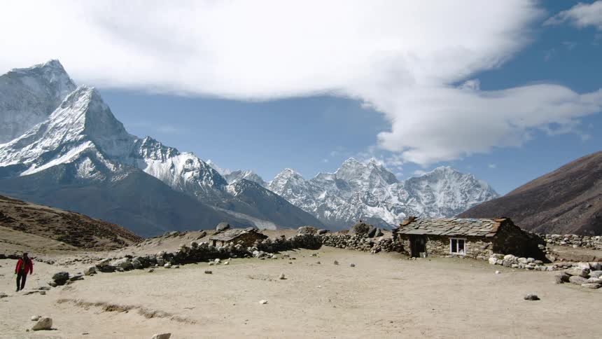 A man walks at the base of the mountains