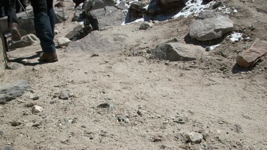 A group of hikers walking across rocky terrain in single file