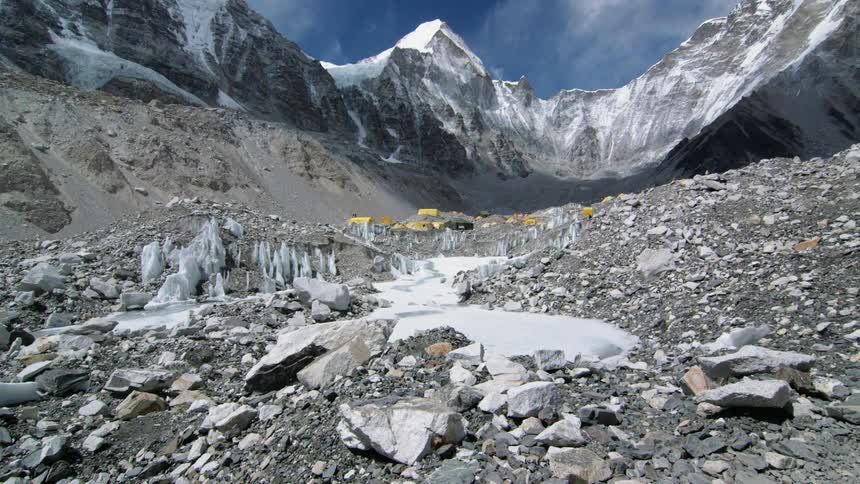 Tents are pitched at the bottom of a mountain range