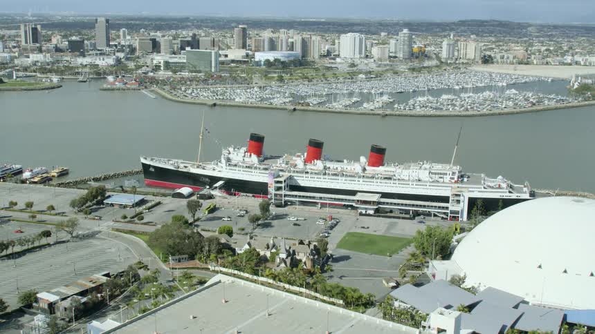 Aerial of queen mary cruise ship docked in long beach with skyline in the distance