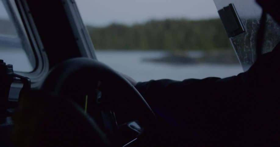 A person pilots a boat across water