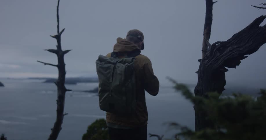 A backpacker takes photos of a lake near a forest