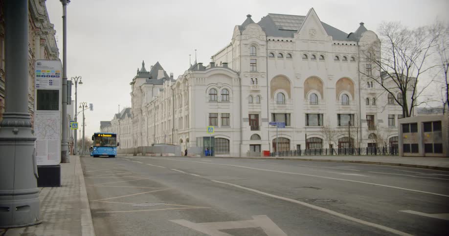 Bus travels down a city street near a large building