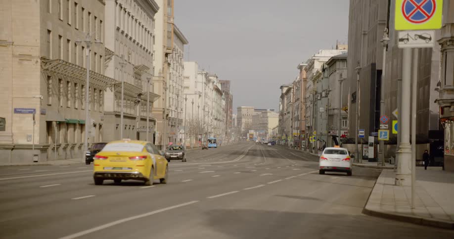 Cars drive down nearly empty road past mid rise buildings