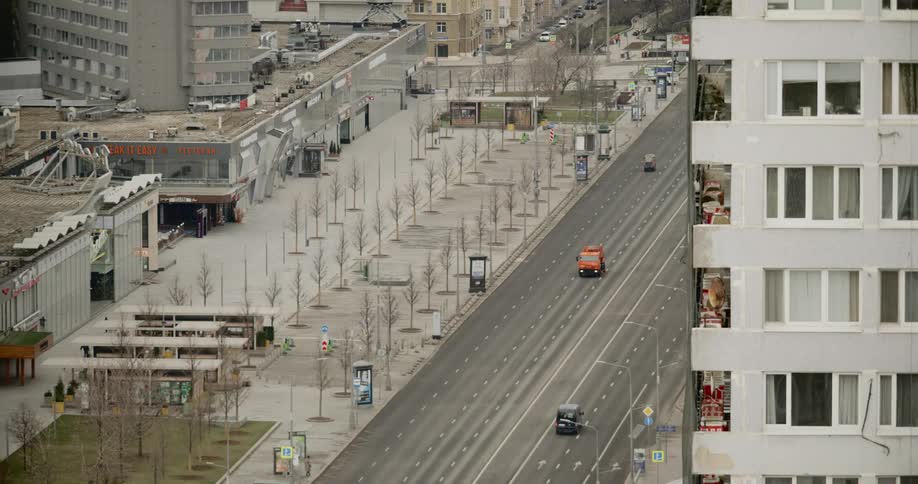 A few vehicles drive through past empty sidewalks and shops