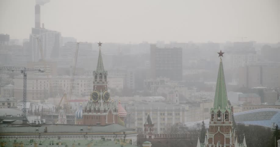 Fog obscures city buildings and factory near clock tower