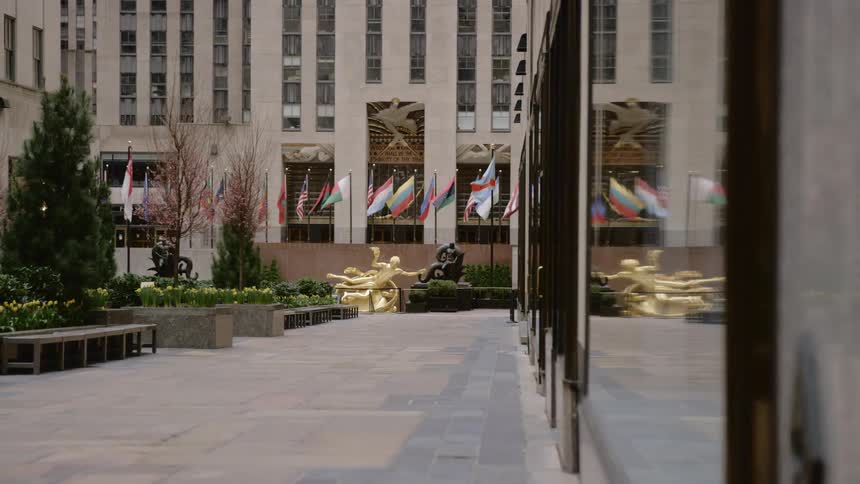 Flags wave in a breeze in front of a city building