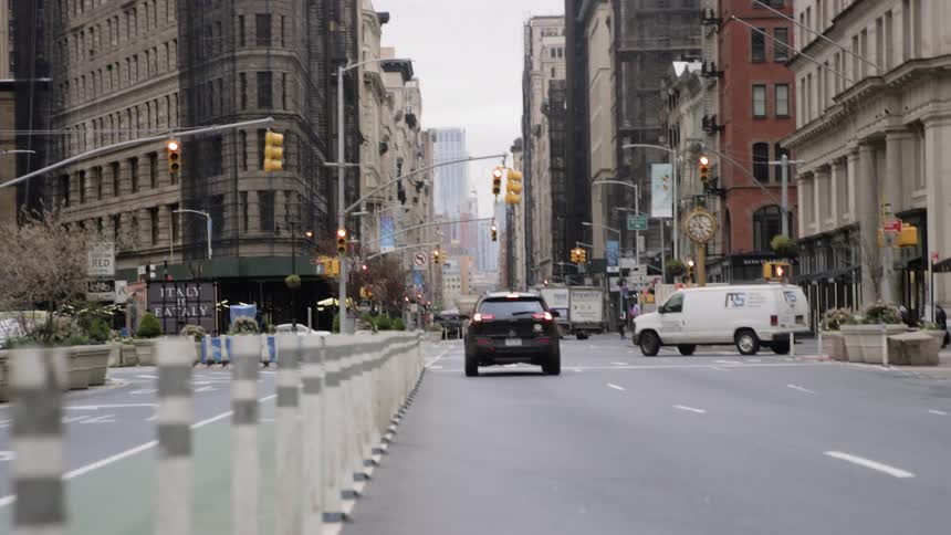 A car waits at a red light as a van turns onto the city street
