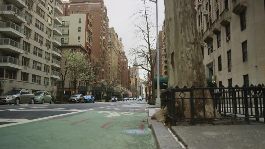 A city street lined with apartment buildings is empty of people