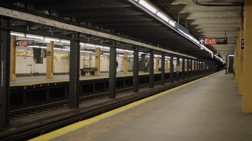 A man carrying bags walks through an empty train station