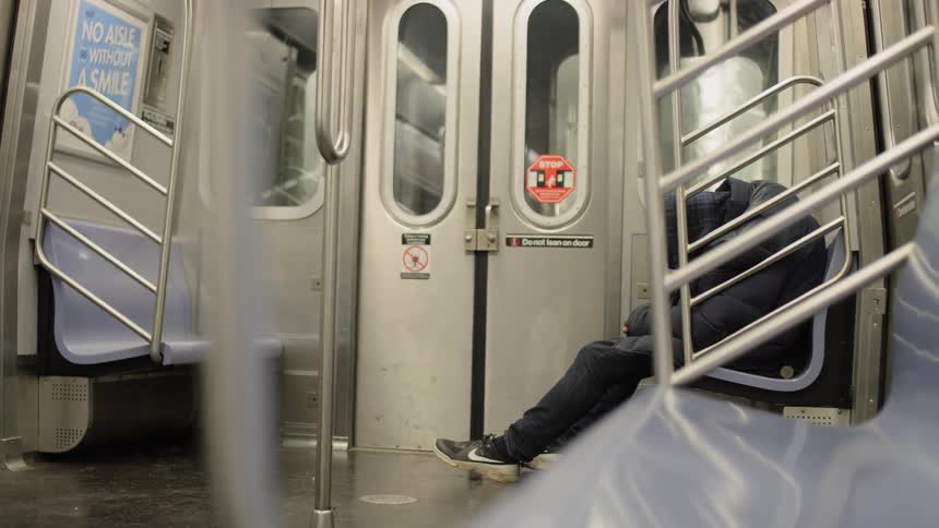 A person is sleeping in the moving subway train